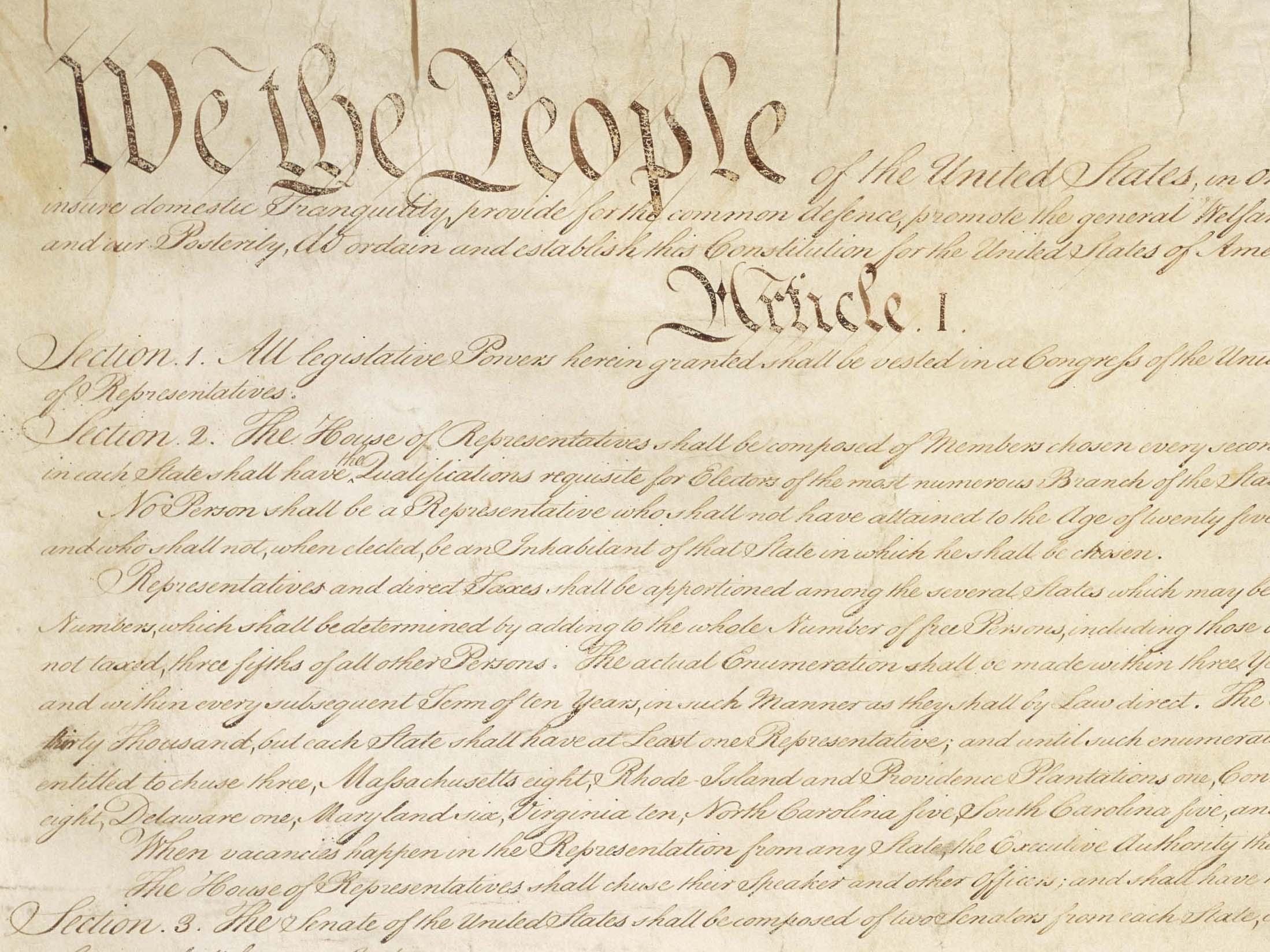 The top of the US Constitution, including large text “We the People”